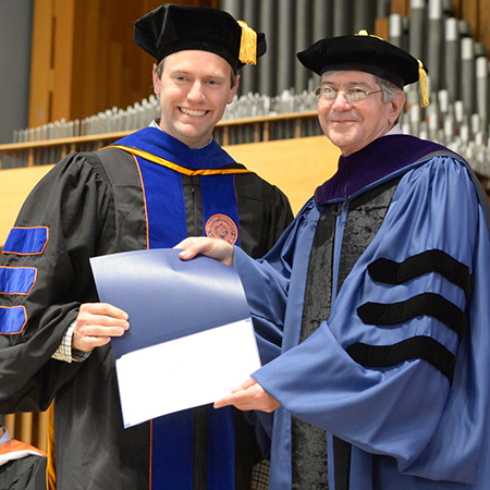 Jim Steinberg presenting a student with a prize at a graduation ceremony