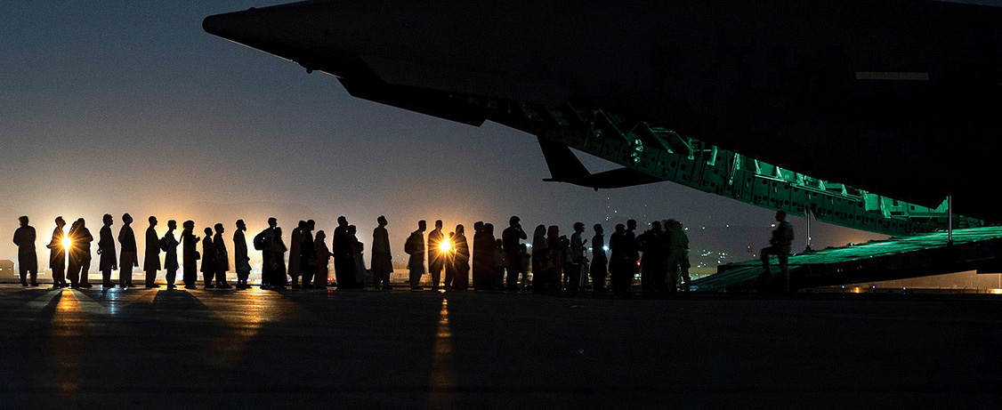 a line of people board an airplane in the night