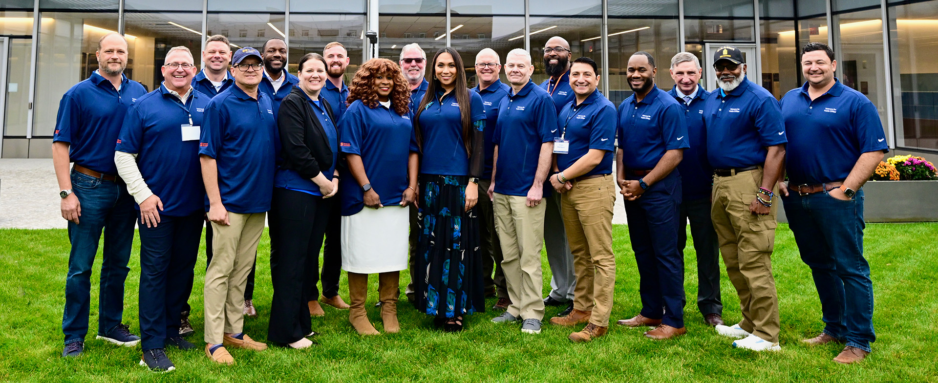 Group of people standing on grass. All are wearing blue polo shirts.