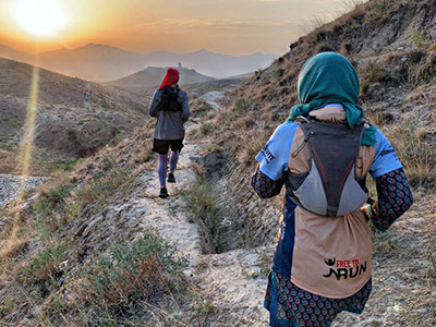 Women run along a path in Afghanistan at sunrise
