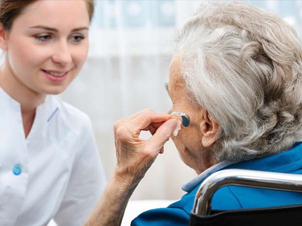 An elderly person putting in her hearing aid