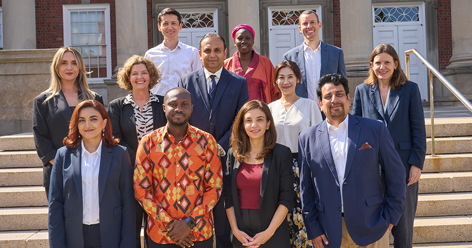 Group of diverse professionals posing on steps in front of a brick building, smiling.