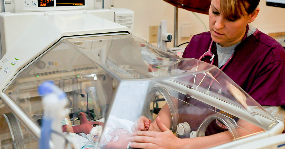 Neonatal intensive care unit nurse checks newborn