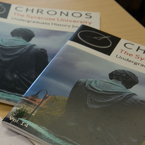 two copies of "Chronos: The Syracuse University Undergraduate History Journal" on a table. Both covers feature the rear view of a statue and are labeled with "Vol. 14.