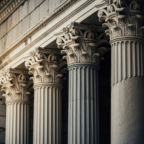 Close-up of ornate Corinthian columns on a classical stone building, showcasing detailed carved capitals and fluted shafts.