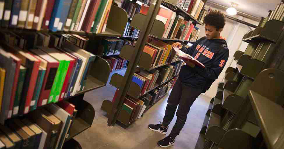 Student flipping through a book in a library
