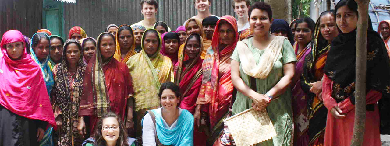 Maxwell faculty and students overseas with large group of women in colorful clothing