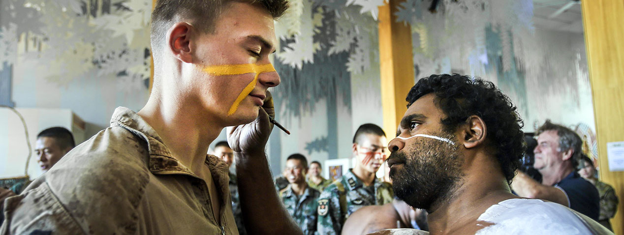 Indigenous Australian applies paint to face of United States marine