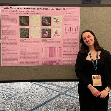 A person smiling beside a research poster titled "Trust in Maps: A mixed-methods cartographic study.