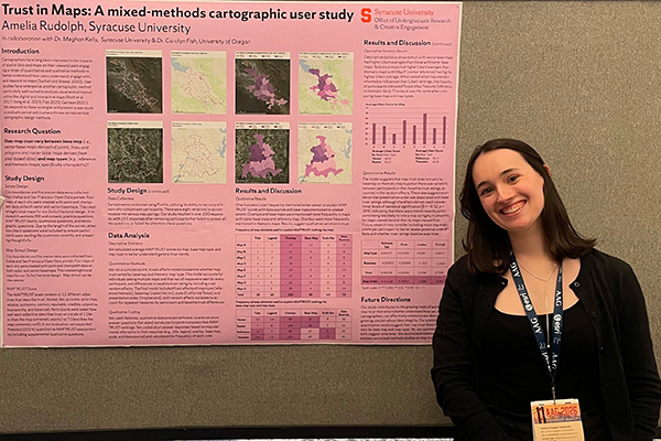 A person smiling beside a research poster titled