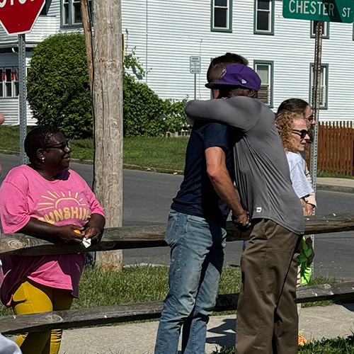 Two people embrace on a sidewalk near a stop sign and Chester Street sign.