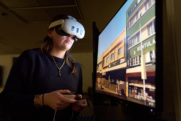 Person using a virtual reality headset to view a streetscape on a monitor.
