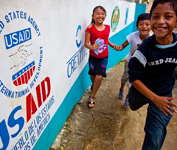 Children running in front of USAID sign