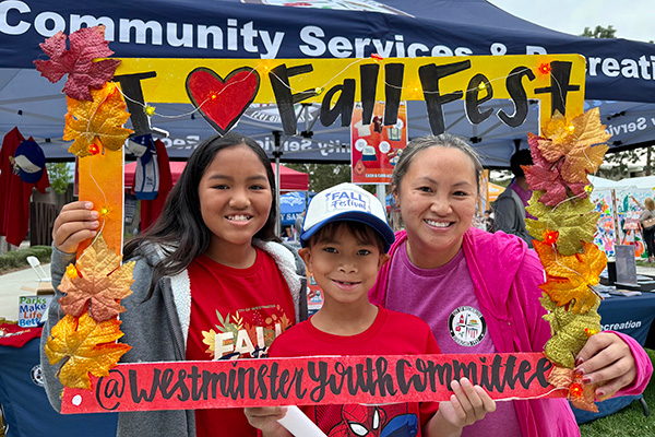 Three people smiling and holding a decorative frame with