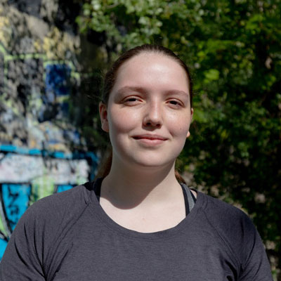 Kiersten Edwards poses in front of a wall with graffiti