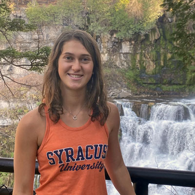 Taylor Fein stands infant of a waterfall