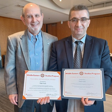 Two men stand together holding Middle Eastern Studies Program award certificates presented to Fethi Keles — a Teaching Recognition Award and a Course Development Grant.