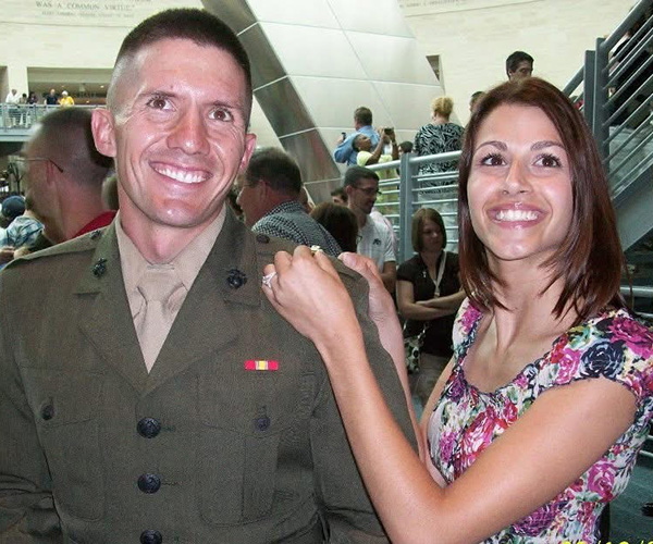 Two people smiling in a busy indoor setting, one wearing a U.S. Marine Corps uniform.