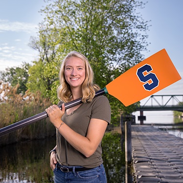 Student Kate Ryan holding a paddle with the Syracuse S logo