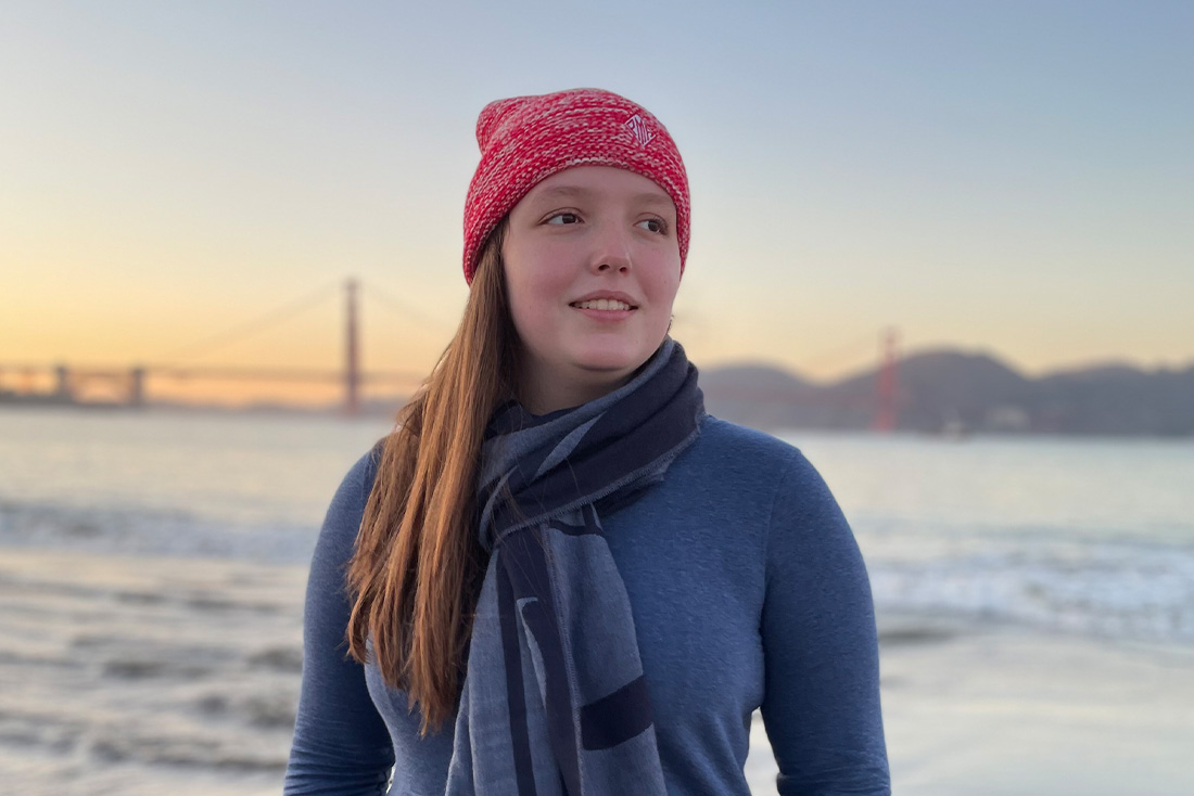 Kirsten stands in front of a bay on the ocean
