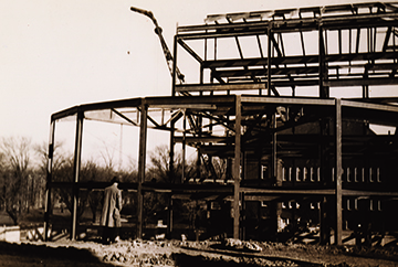 The skeleton frame of Maxwell Hall, with a construction crane in the background