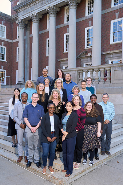 Group of diverse professionals posing on steps in front of a building with classical columns.
