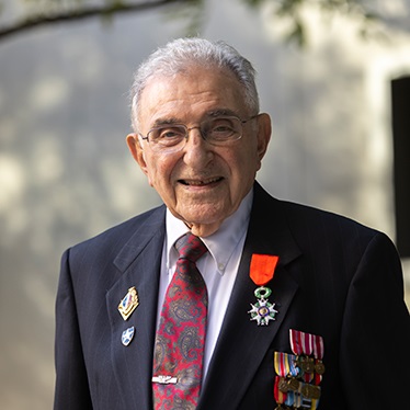 Photo of elderly man with military honors pinned to his suit jacket