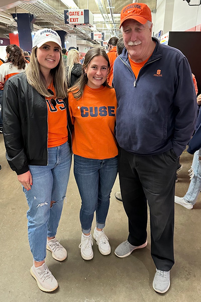 Three people in Syracuse gear pose together at the Dome during a game.