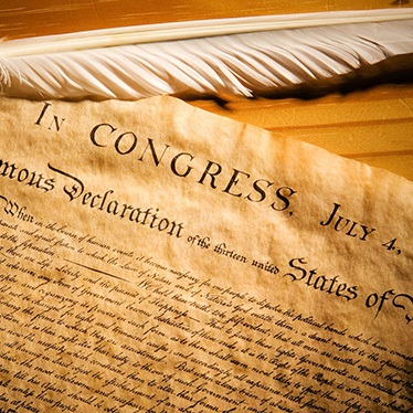A close-up photo of the United States Declaration of Independence, highlighting the document's elegant script and the date "July 4.