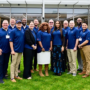 Group of people smiling and wearing blue polo shirts.
