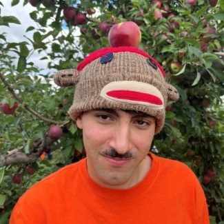 Photo of a person wearing a monkey hat and an orange shirt.