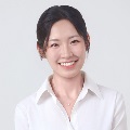 A person smiling in white collared shirt with a delicate necklace.