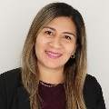 Professional headshot of a smiling individual with long hair, wearing a dark blouse and a gold necklace.