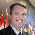 Portrait of an individual smiling in front of international flags.