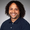Portrait of a smiling person with dark curly hair