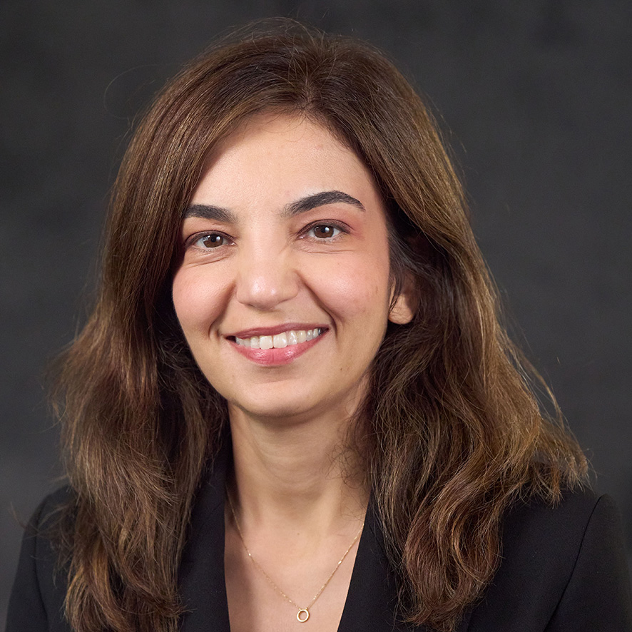 Official portrait of a professional smiling, wearing a black blazer and a necklace.