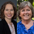 Portrait of two people. The person on the left is wearing a black jacket and a patterned blouse, with a pleasant smile. The person on the right is dressed in a blue blouse, smiling warmly at the camera. Both are set against natural backgrounds.