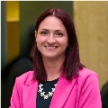 Portrait of an adult in a bright pink blazer, smiling at the camera.