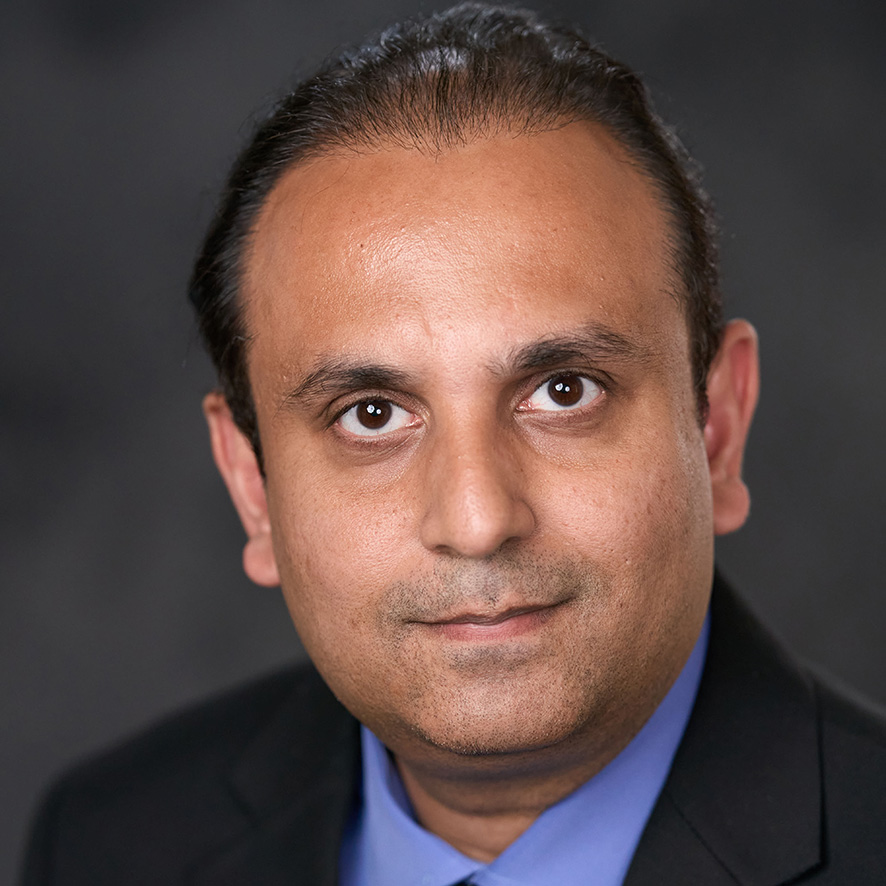 Portrait of a professional wearing a dark blue shirt, featuring a neutral background.