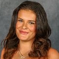 Portrait of a person smiling with long brown curly hair.