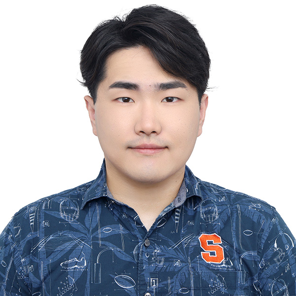 Portrait of a person wearing a blue shirt with various scientific and engineering diagrams, including an 'S' logo on the chest.