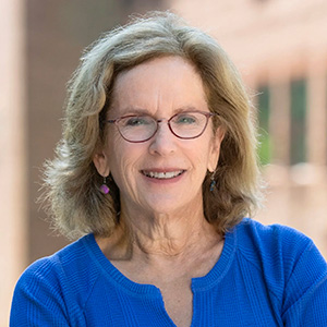 Portrait of a person smiling and wearing glassses and a blue top.