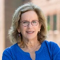 Portrait of a person smiling and wearing glassses and a blue top.