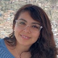 Headshot of a smiling person with dark hair and glasses.