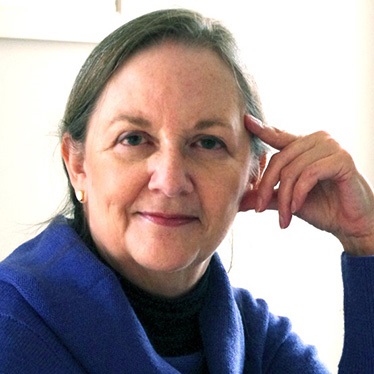 A person with hand near temple, short hair, wearing a blue scarf and top.