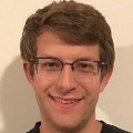 Close-up portrait of a smiling person with glasses.
