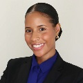 A person smiling in dark blazer over royal blue blouse.