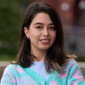 A person smiling in pink and teal patterned cardigan over light blue top