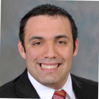 Portrait of a smiling person in a dark suit and red-striped tie.