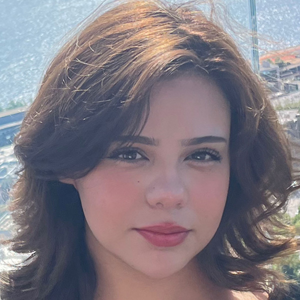 Close-up portrait of a person with short wavy hair, against a blurred background.